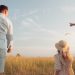 man in white dress shirt and woman in brown dress standing on green grass field during
